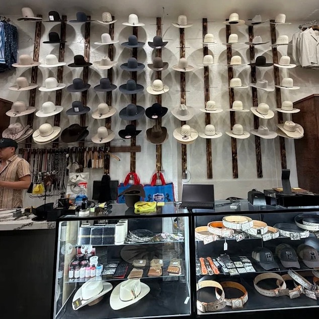 Inside the San Luis Obispo store: the hat wall on burnt timber rails above the belt and accessory counters